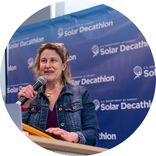 Woman stands at podium with microphone speaking to audience